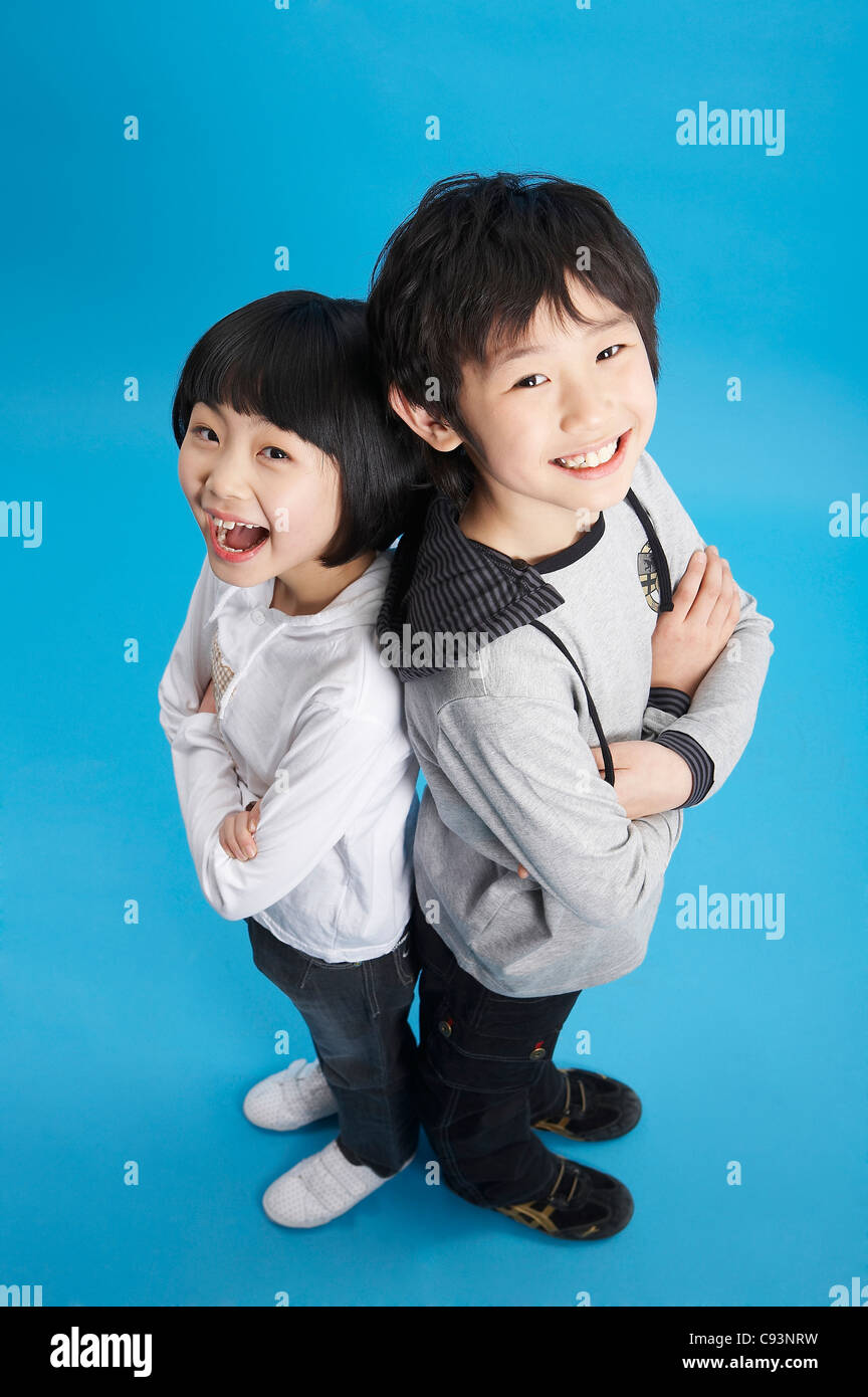 Boy and girl standing back to back, studio shot Stock Photo - Alamy