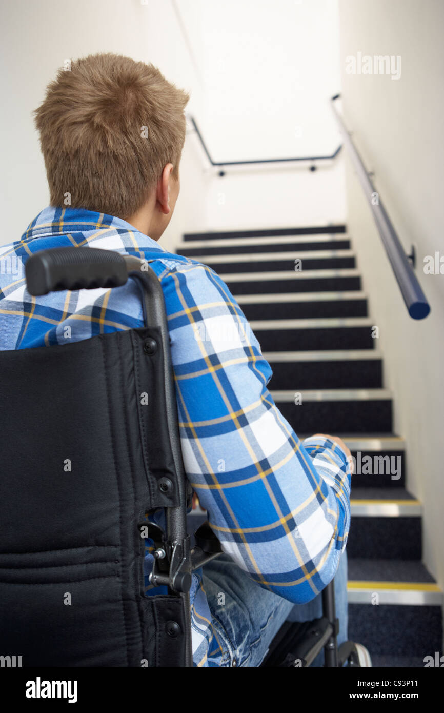 Man in wheelchair at foot of stairs Stock Photo