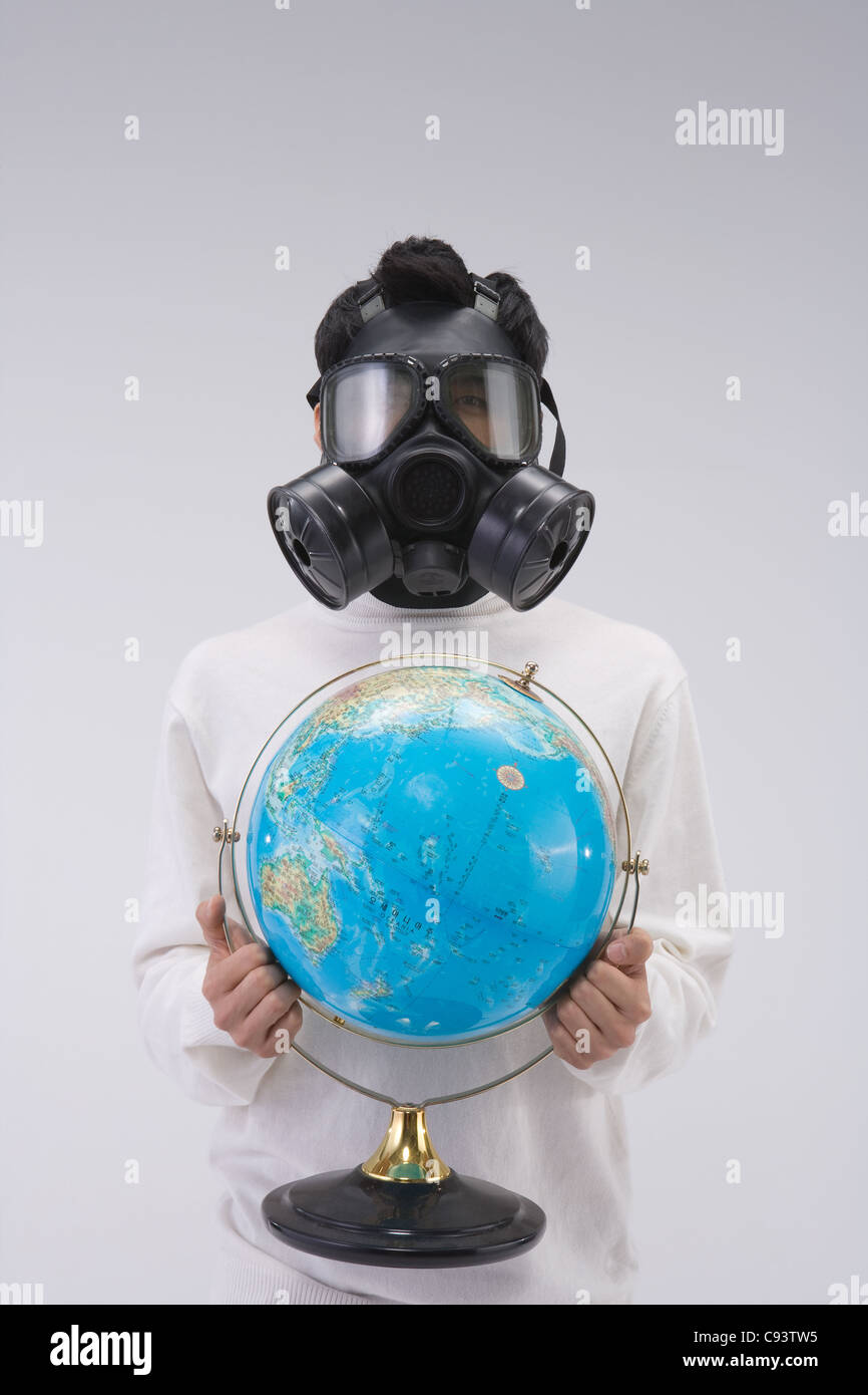 Studio shot of man wearing oxygen mask with holding globe Stock Photo