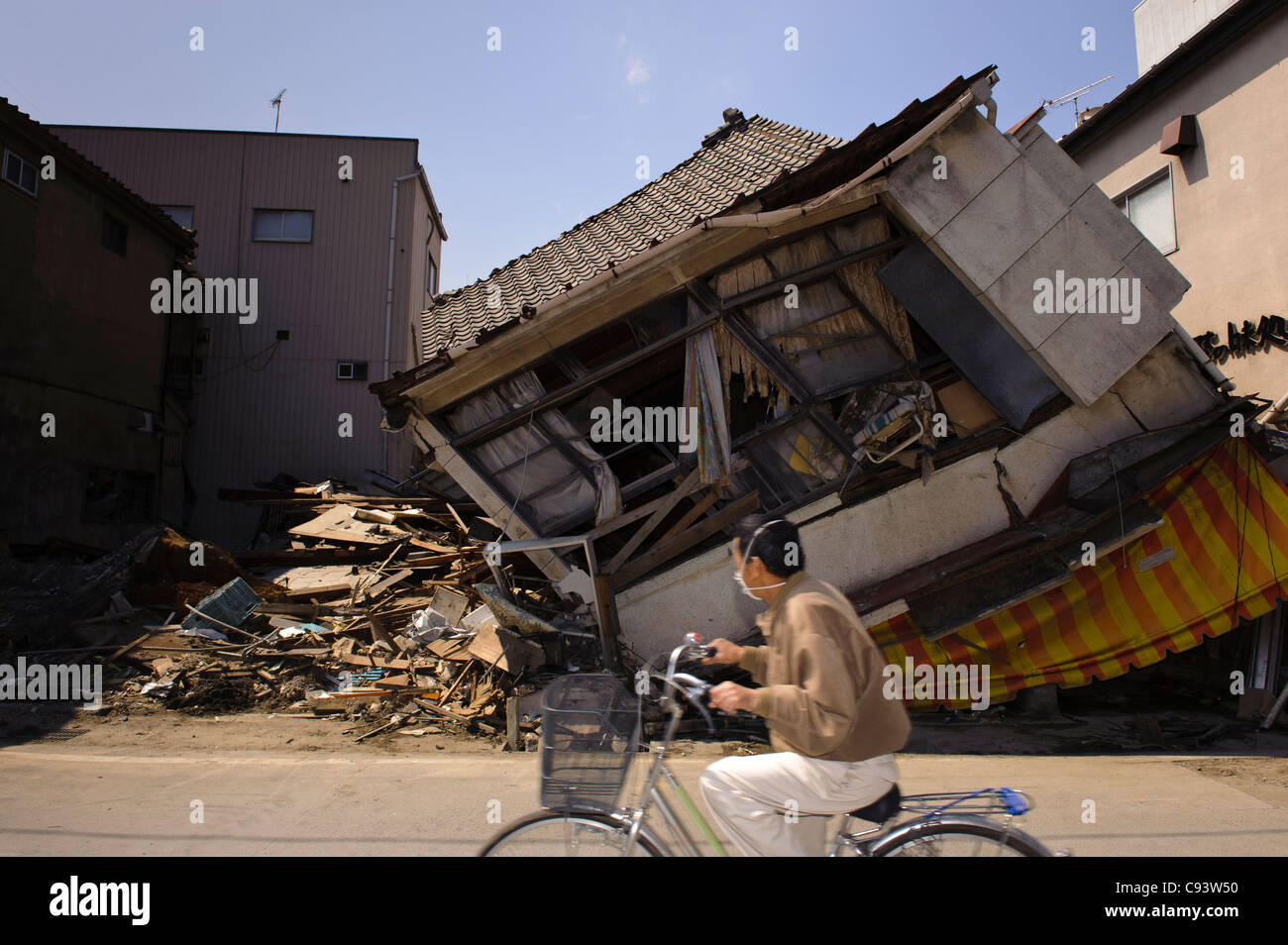 Man riding bicycle beside buildings damaged by the March 11 tsunami, Ishinomaki, Miyagi Prefecture, Japan Stock Photo