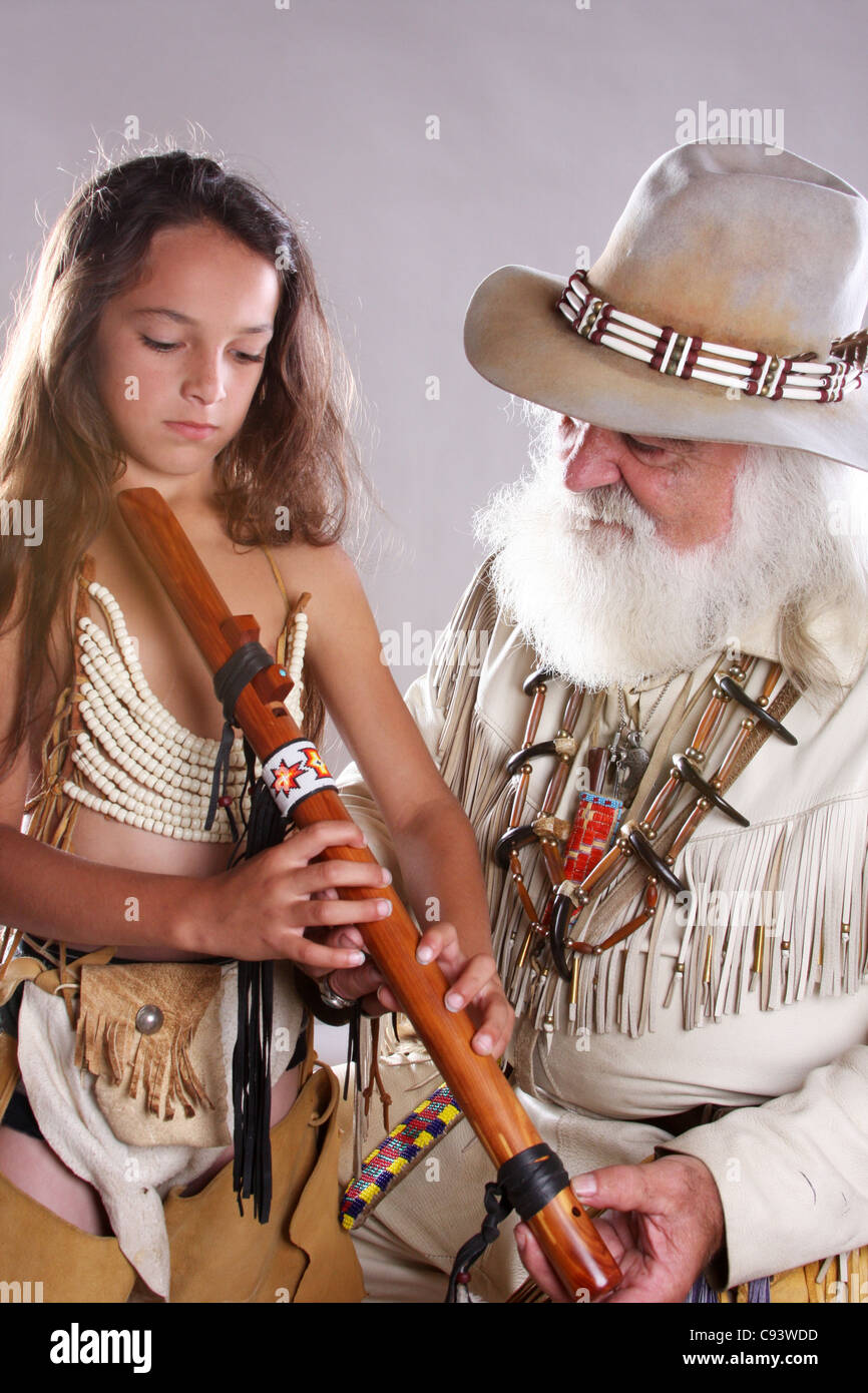 A mountainman teaching a young Native American Indian boy how to play the flute Stock Photo