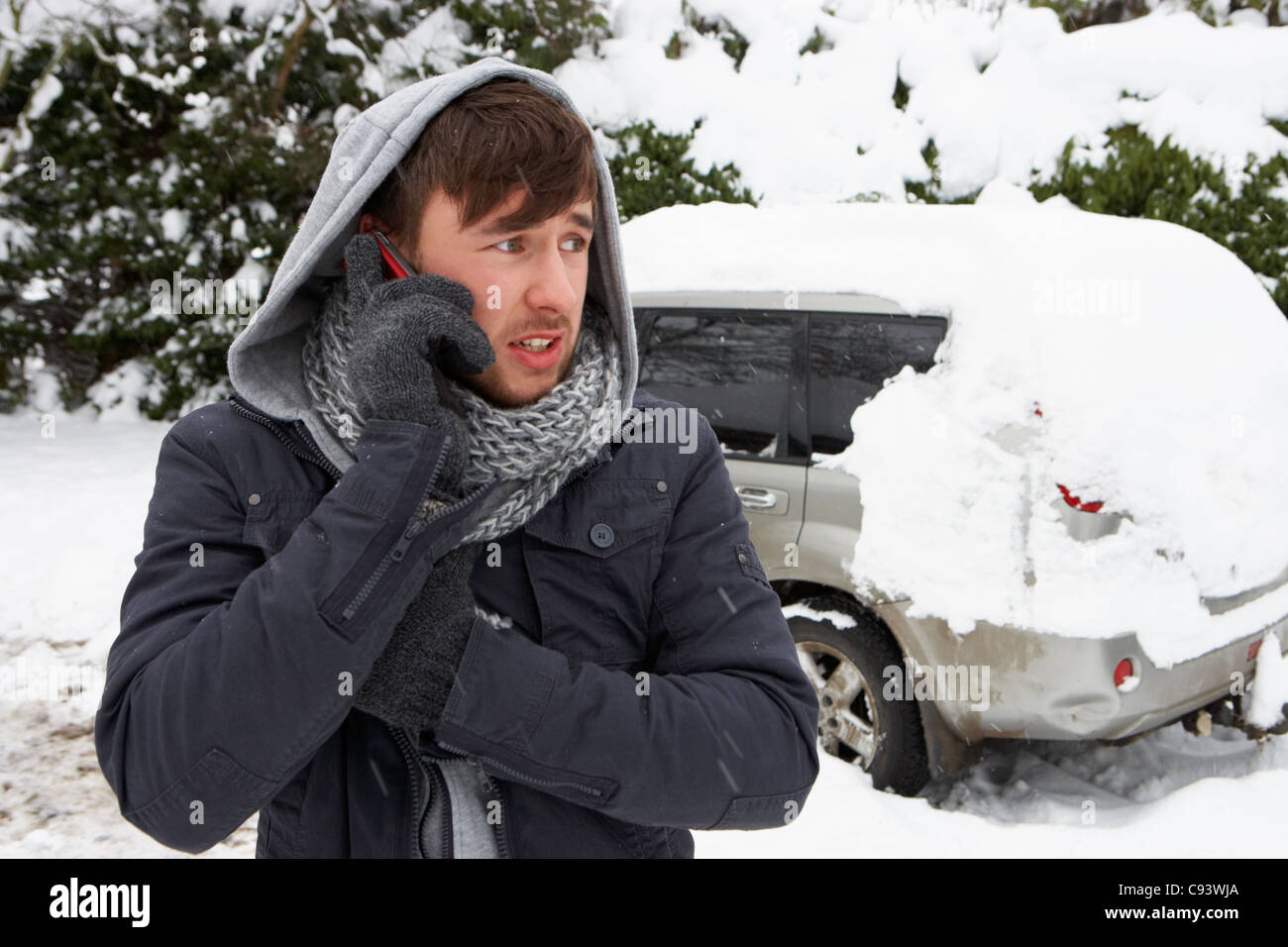 Young man in snow with broken down car Stock Photo