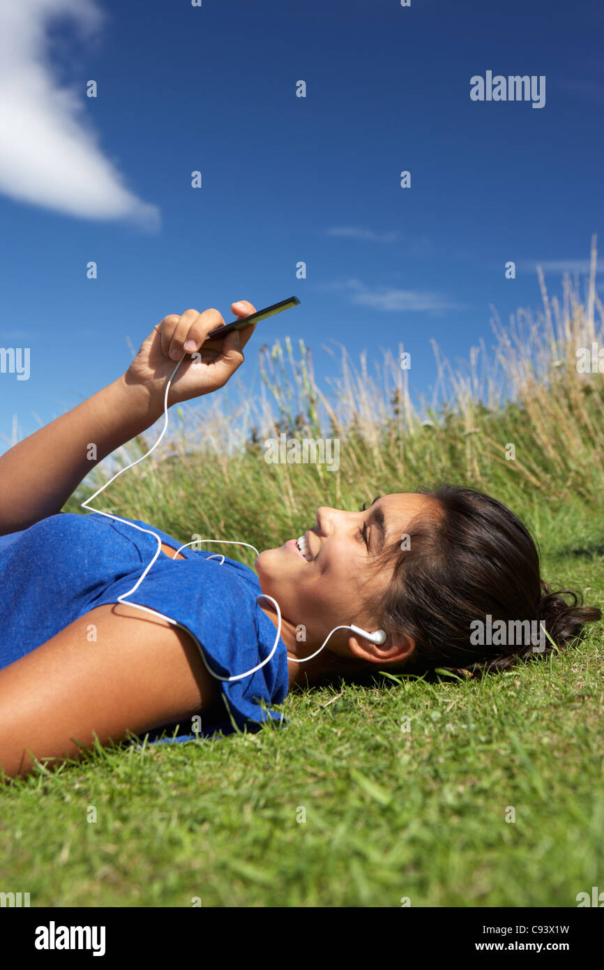 Teenage girl lying on grass with mp3 player Stock Photo