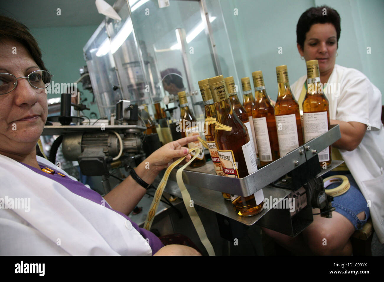 Workers stick labels at the bottles at the rum factory Fabrica de