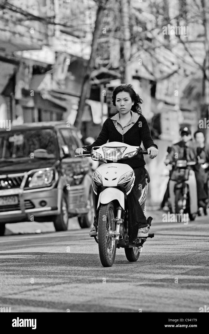Asia, Vietnam, Hanoi. Hanoi old quarter. Young vietnamese woman riding a small motorbike through Hanoi. Stock Photo