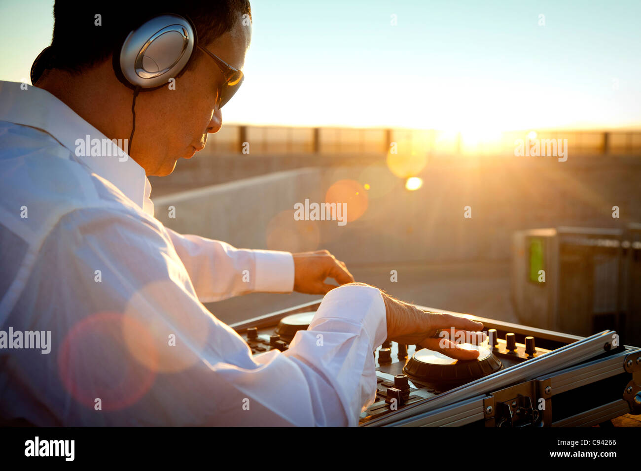 DJ Using Mixing Console at Sunrise Stock Photo