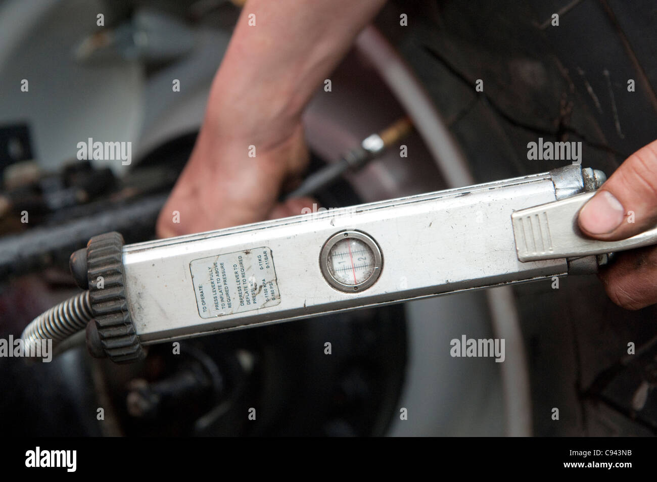 Mechanic checking the tyre pressure in tractor tyres Stock Photo