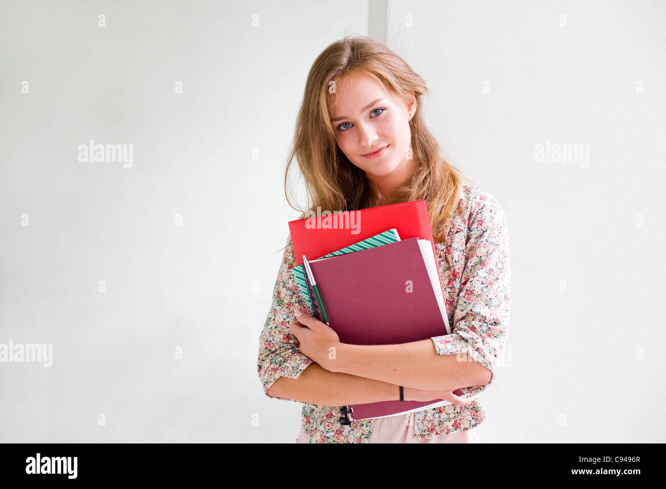 Portrait of cute young blond student girl holding exercise books Stock ...