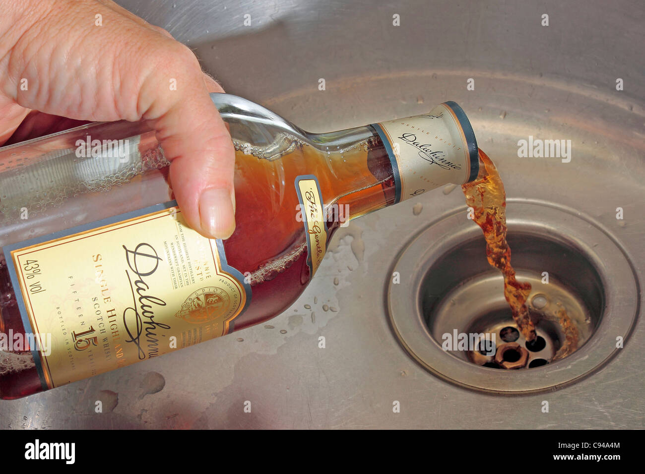 Pouring whisky away down the sink Stock Photo