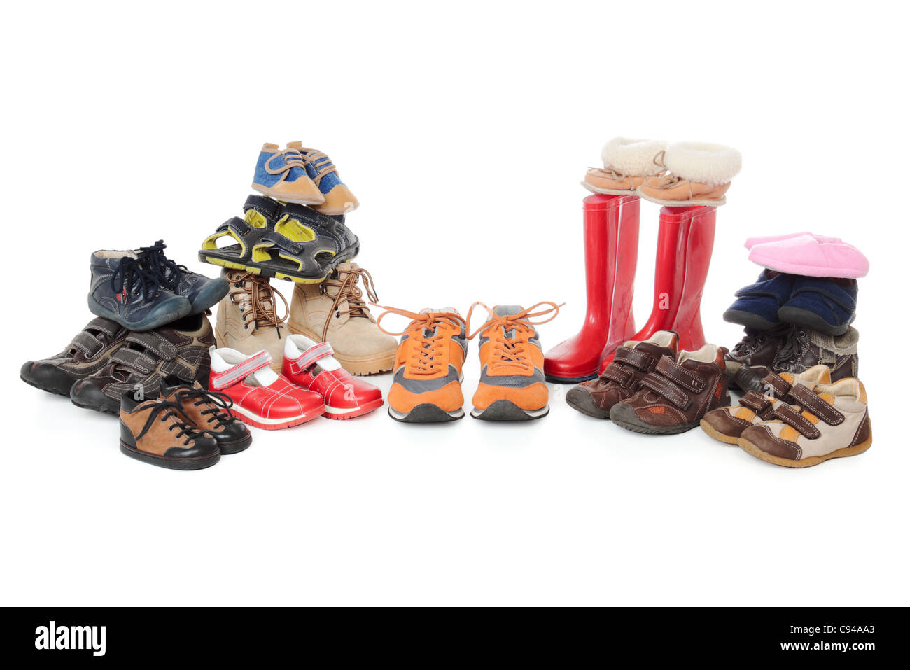 Large group of child footwear isolated over white background. Shoes organised in stacks and symmetrical line. Stock Photo