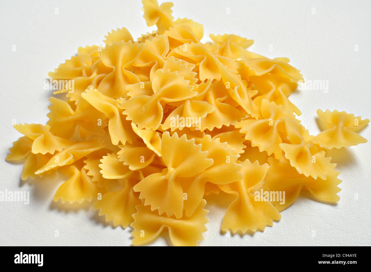 A small pile of dried Farfalle pasta sits on a white background. Stock Photo