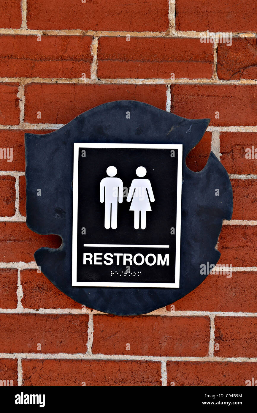 A restroom sign on a brick wall Stock Photo