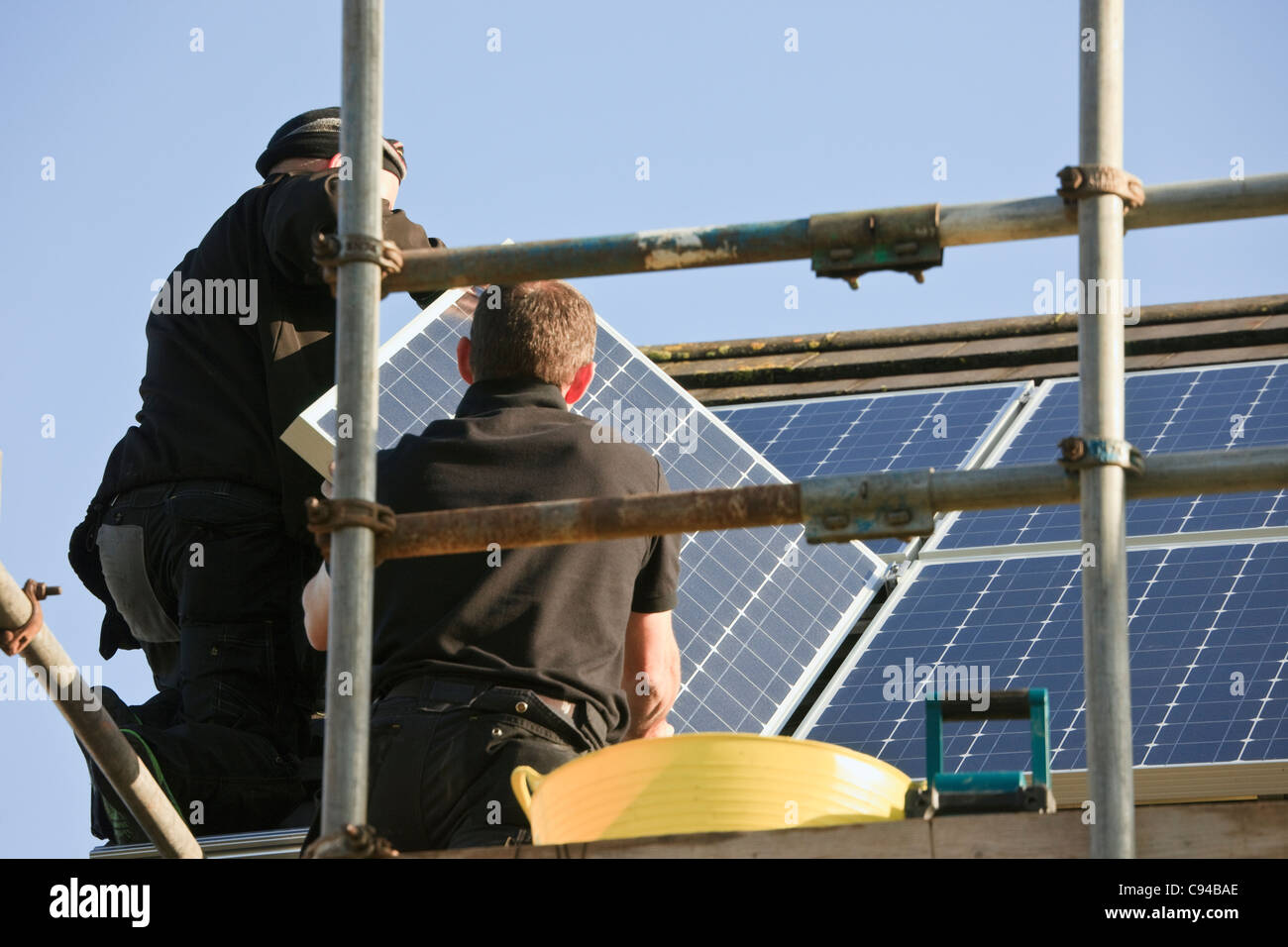 Workmen installing new solar panels to a house roof for the Feed-in Tariff scheme. Wales, UK, Britain Stock Photo
