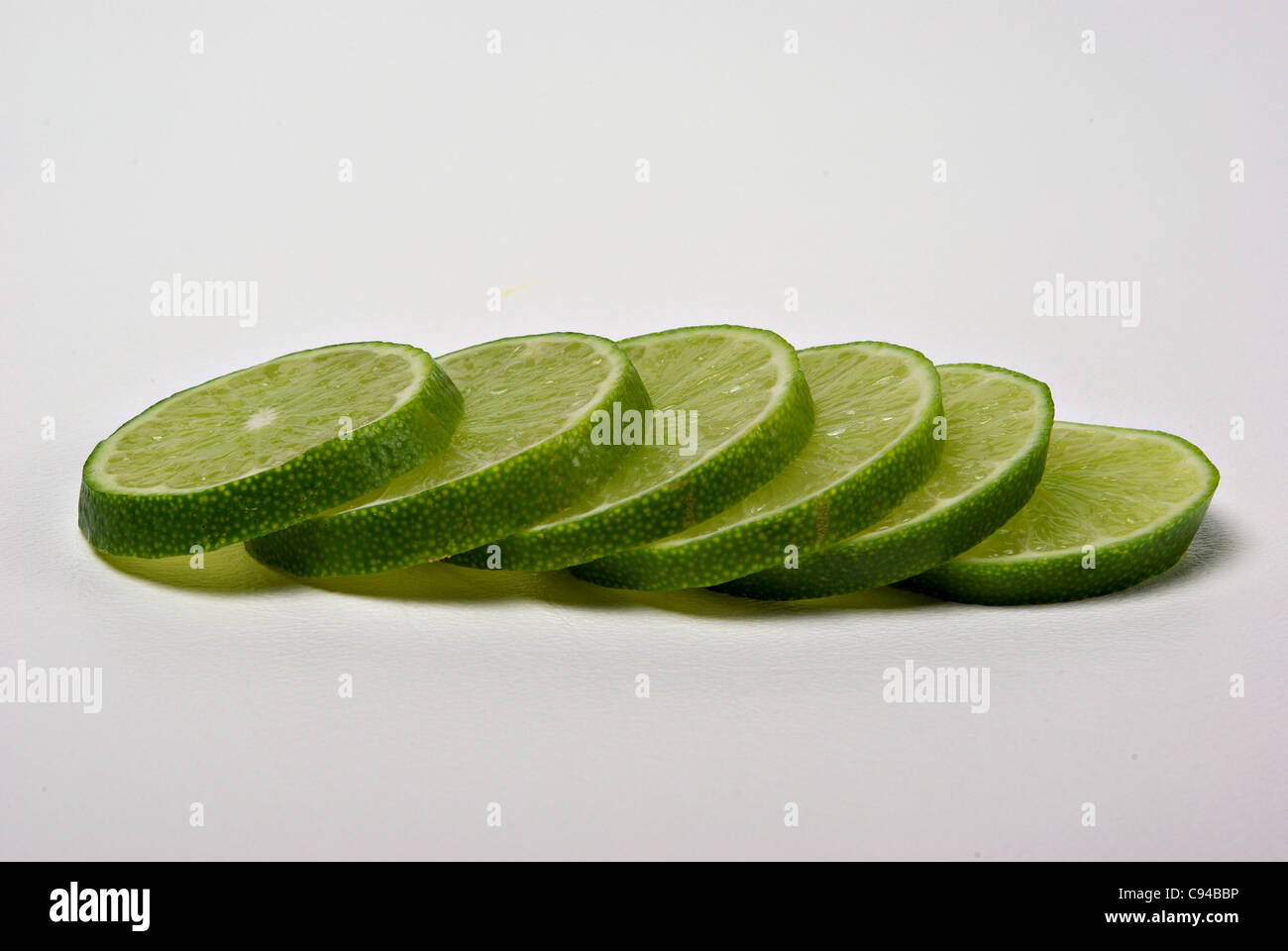 Lime slices lay on a plain background. Stock Photo