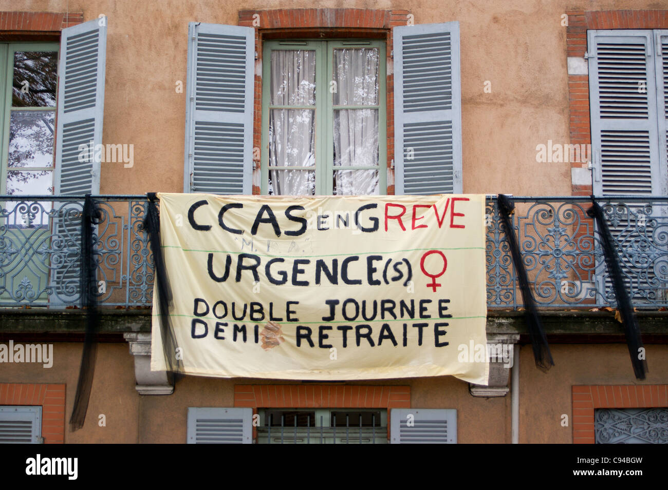 Strike banner on a balcony with louvred window shutters,  Toulouse, Haute-Garonne, Midi- Pyréneés, Occitanie, France Stock Photo