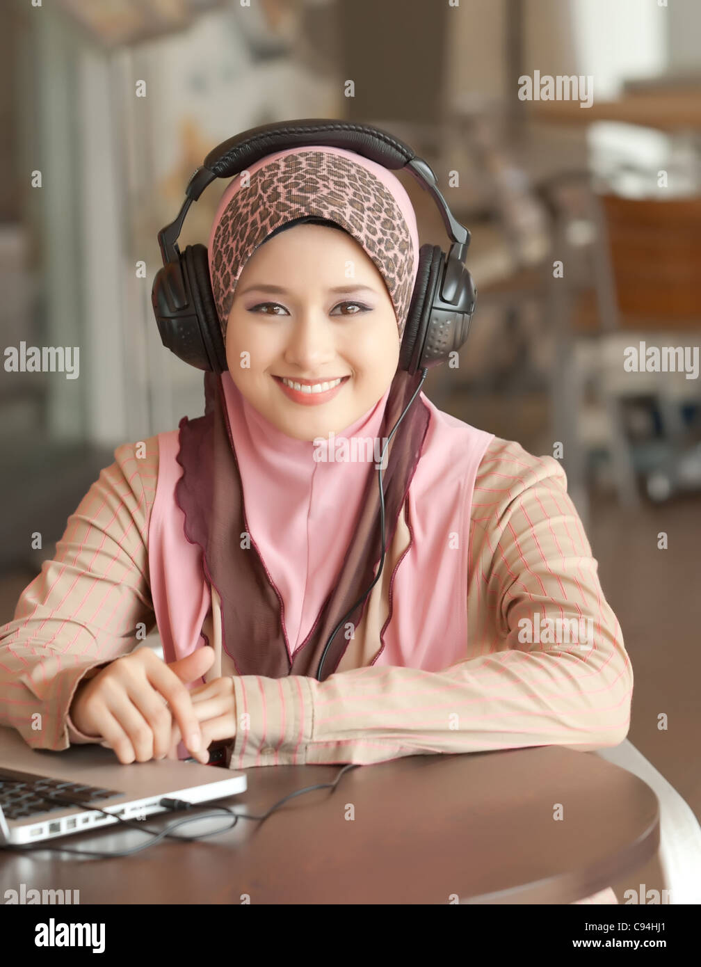 Muslim young girl wearing headphone on the coffee table Stock Photo