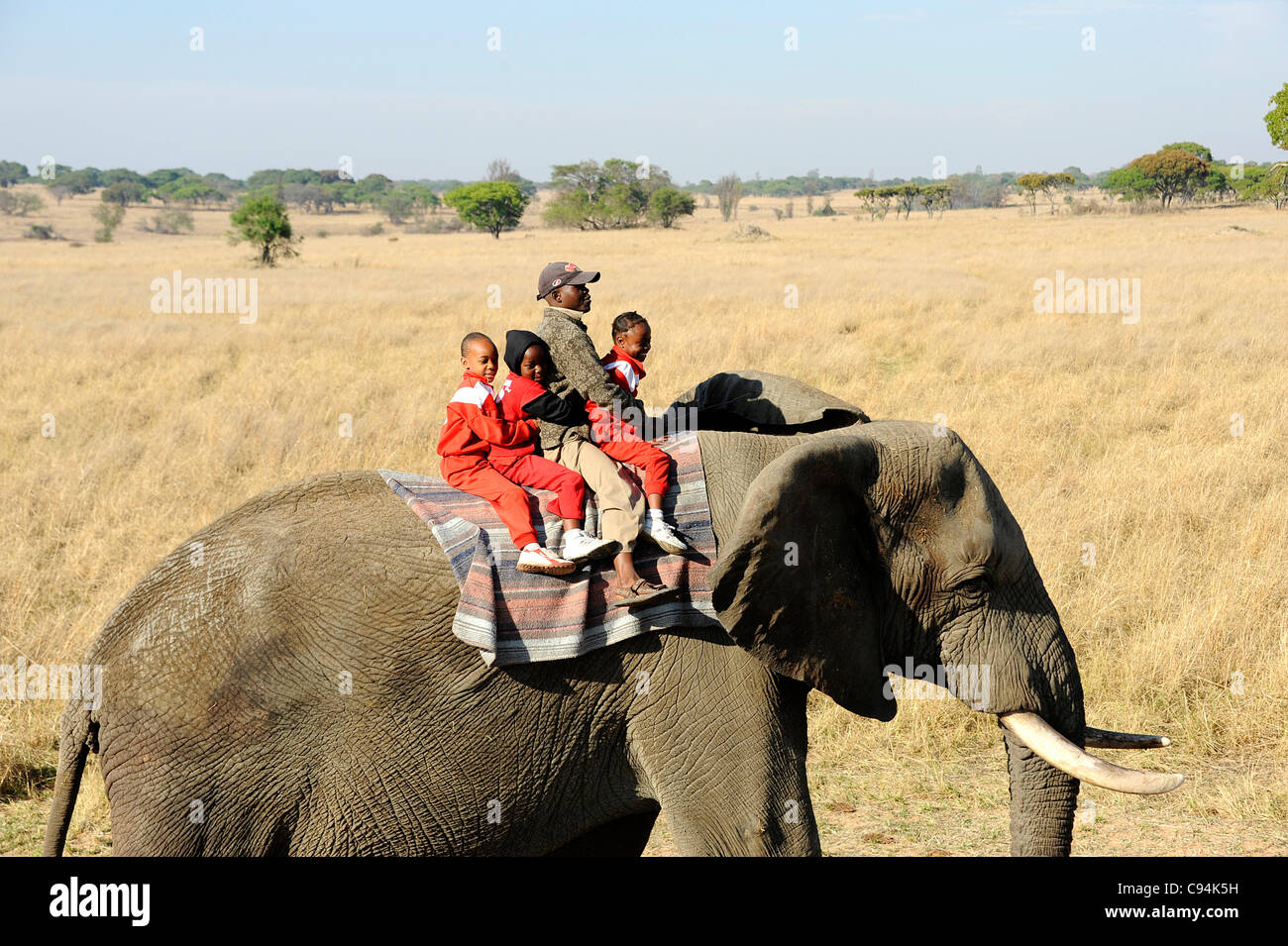 Children riding elephants bareback in Imire Safari Ranch, Zimbabwe