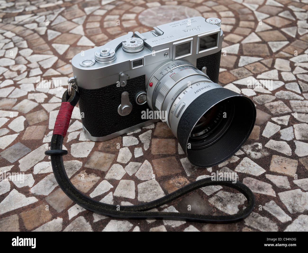 Leica M3 rangefinder camera sitting in a garden table with a mosaic patterned top. Stock Photo
