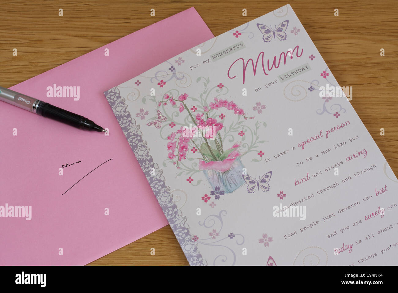 birthday card pen and pink envelope against wooden table background