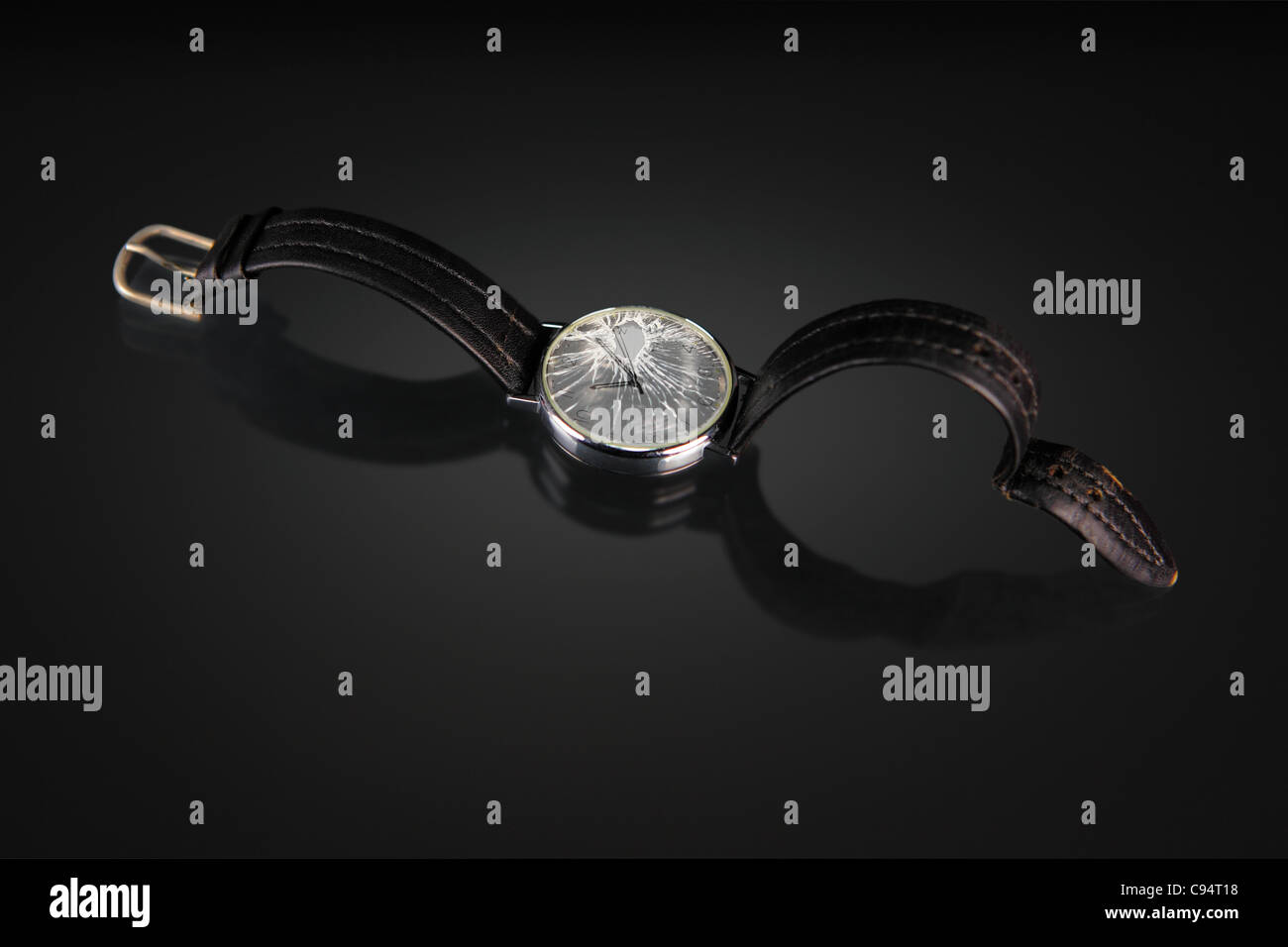 a watch with cracked face on dark reflective table. Low key Stock Photo