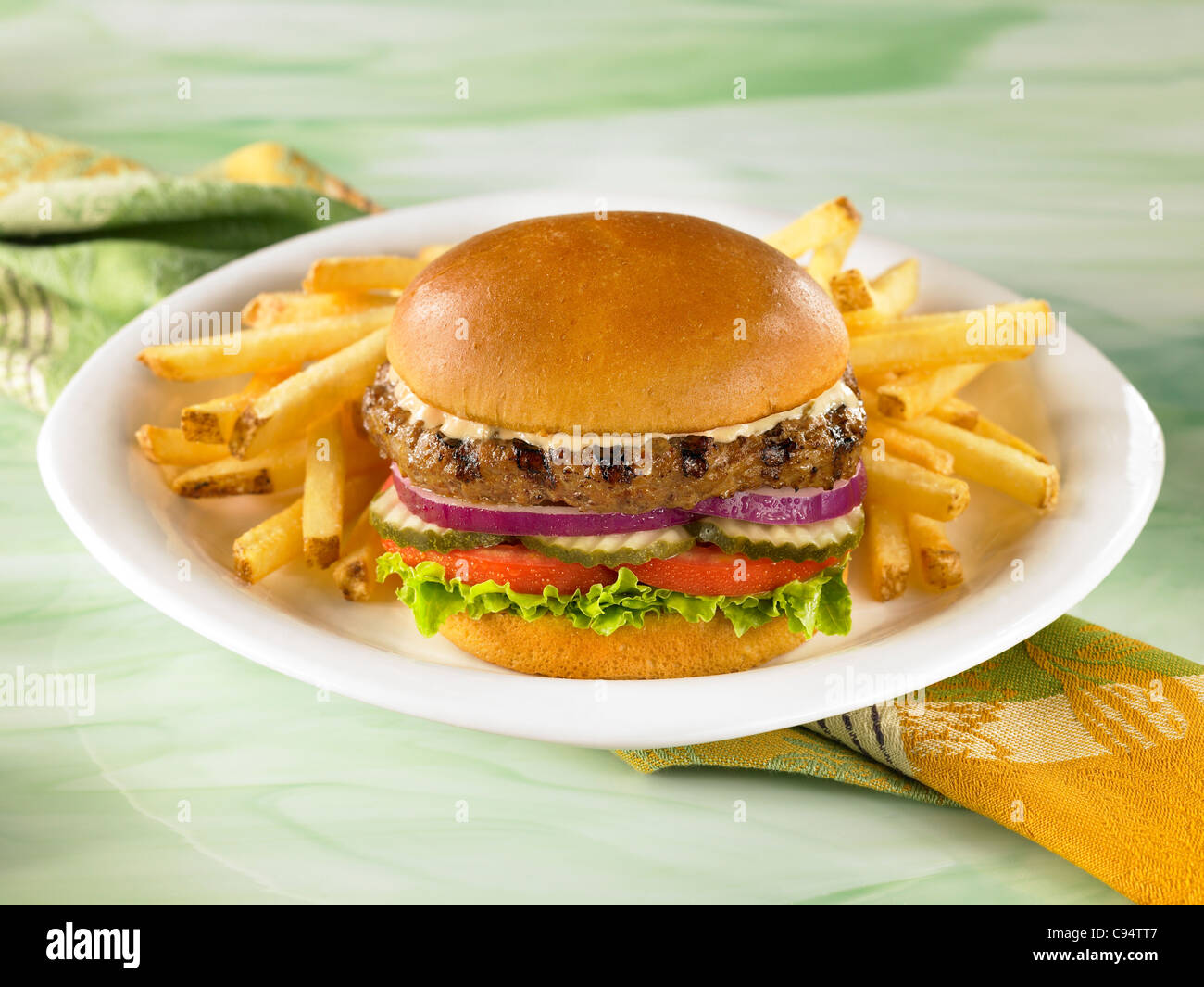 Hamburger on a bun with lettuce, tomato, pickles and onions served with