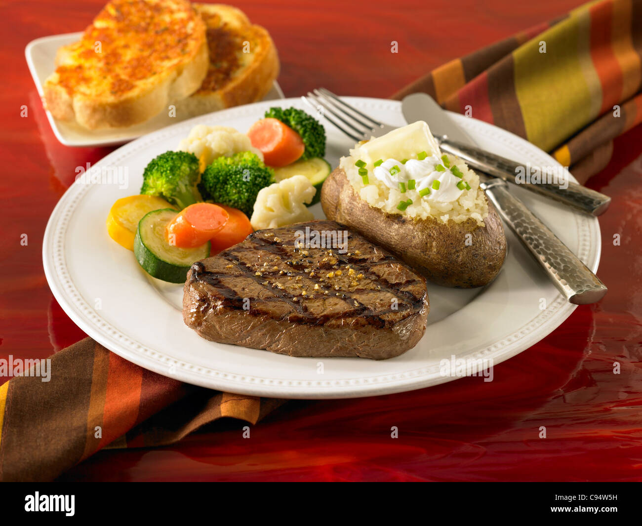 Top Sirloin steak with a loaded baked potato, vegetables and garlic ...