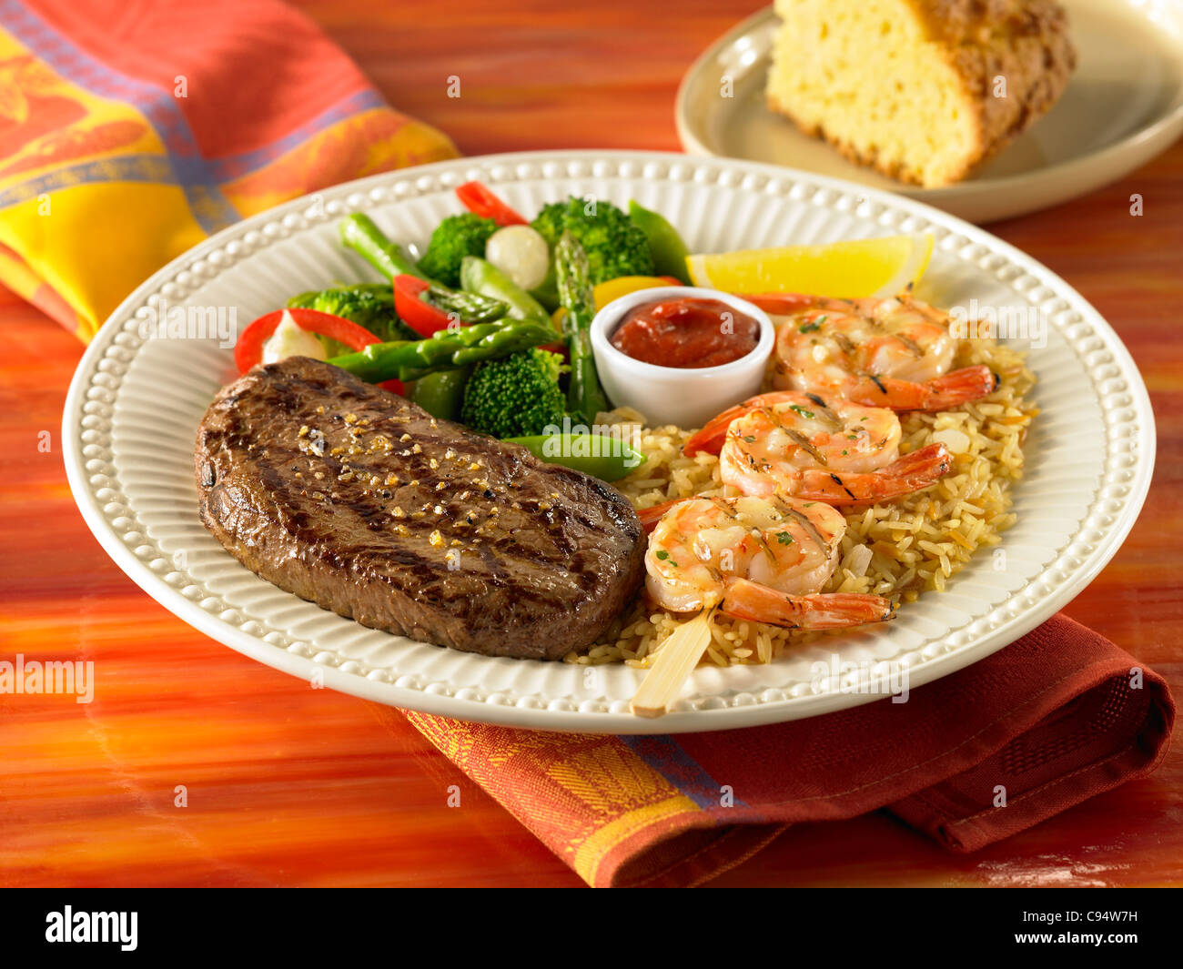 Sirloin and grilled shrimp dinner over rice served with vegetables