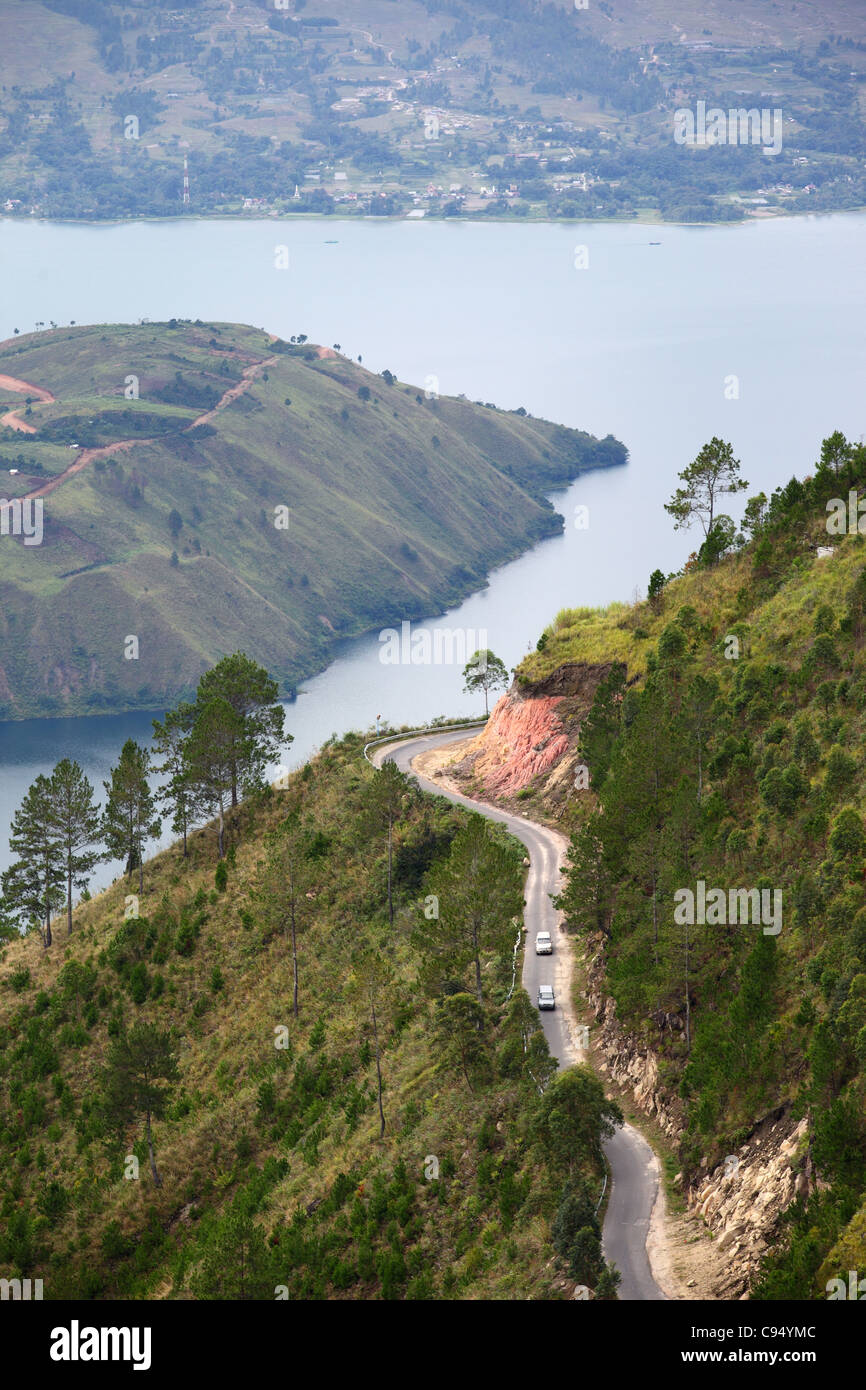 Cars of steep winding road high above Lake Toba in Sumatra. Stock Photo