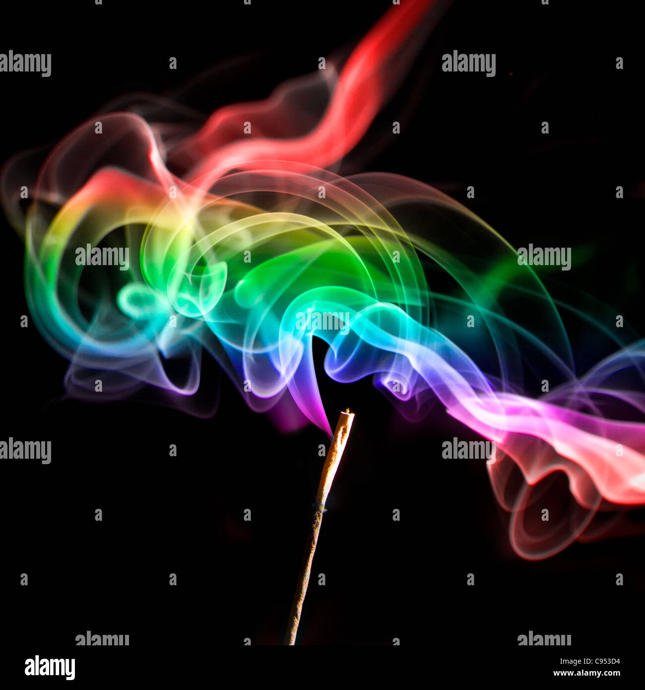 Swirling multi coloured smoke from a Joss stick on a black background Stock Photo