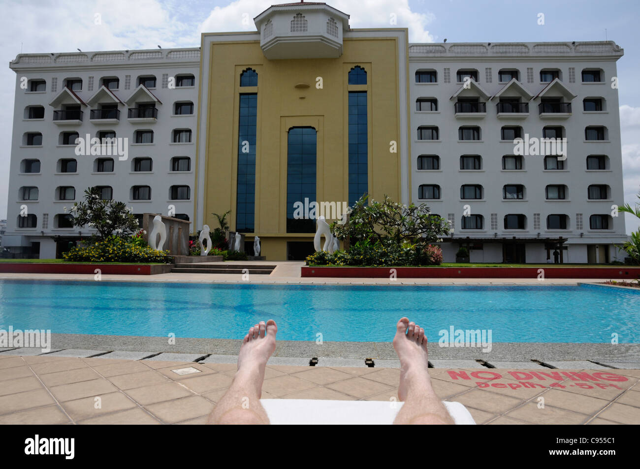 Man on sun lounger relaxing next to hotel pool on holiday. Stock Photo
