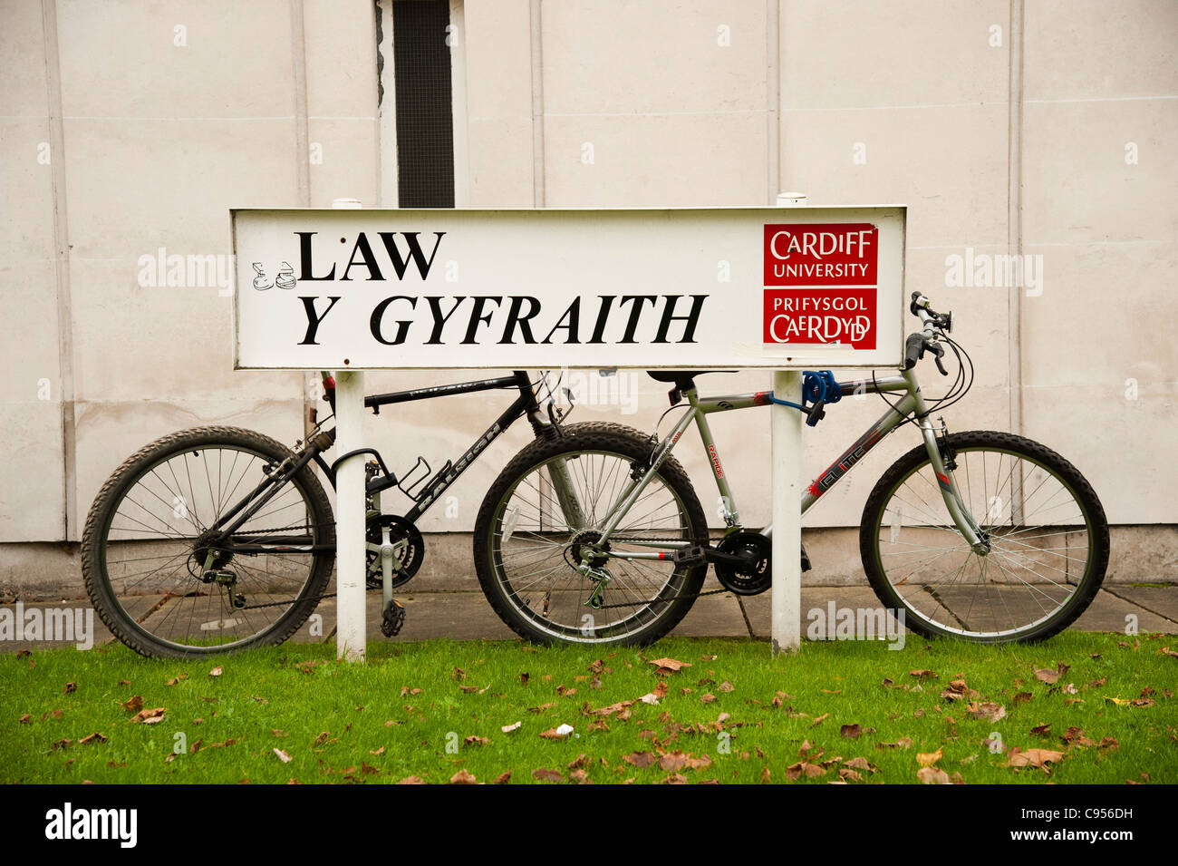 two bicycles resting on a  bilingual welsh english sign outside the School of Law, Cardiff University, Wales UK Stock Photo
