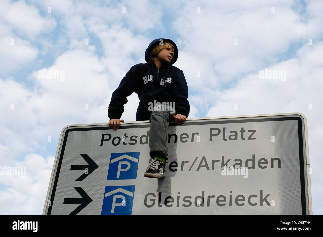 A young boy climbed on a traffic sign from Potsdamer Platz in the center of Berlin, Germany. Stock Photo