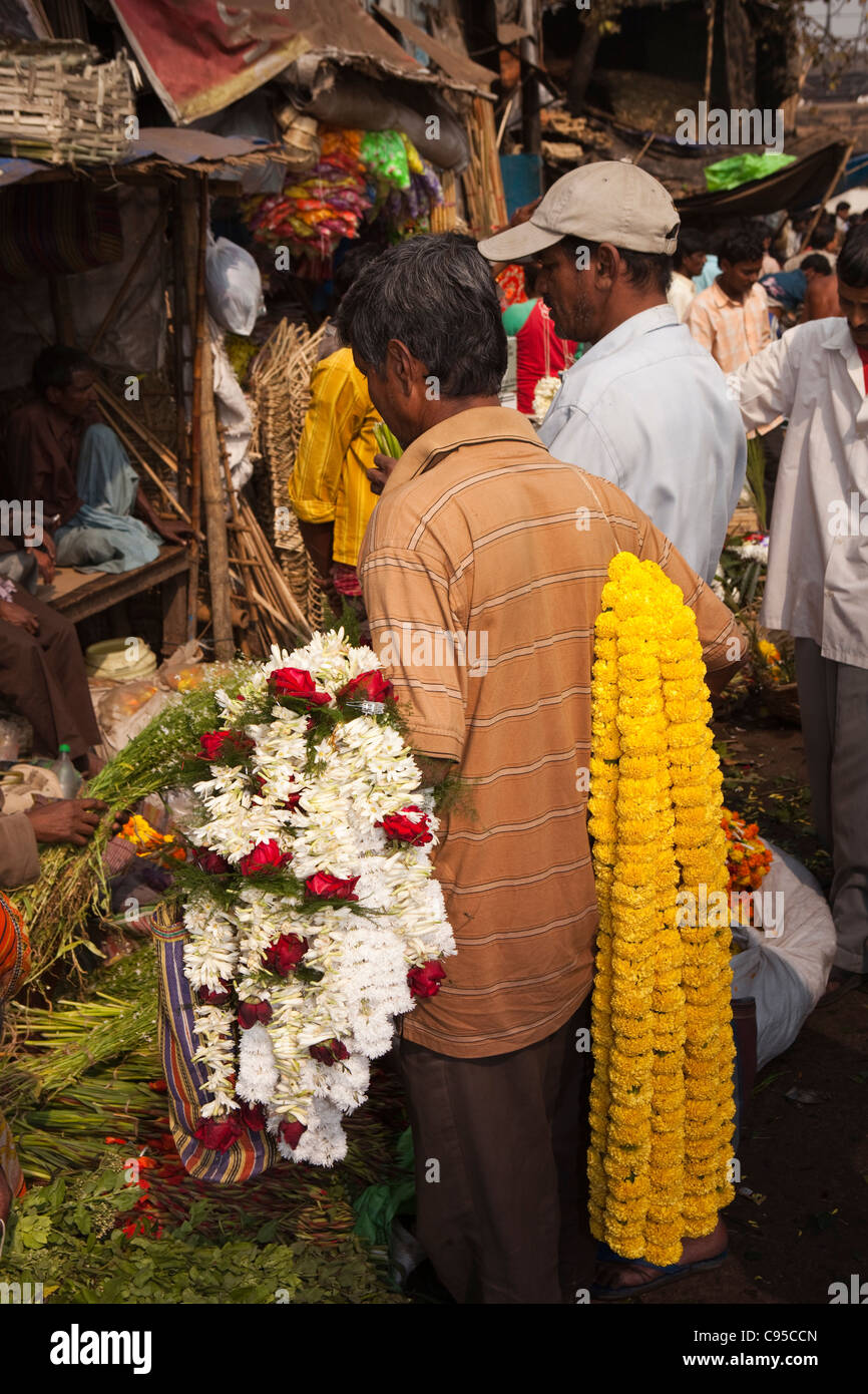 India, West Bengal, Kolkata, Mullik Ghat, flower market, man carrying garlands of marigolds and jasmine Stock Photo
