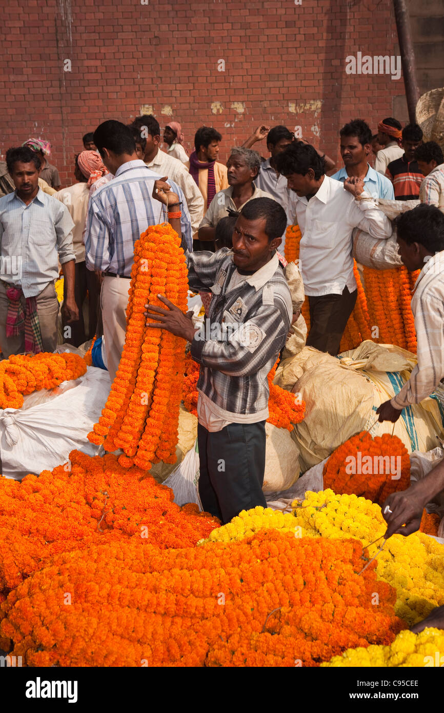 India, West Bengal, Kolkata, Mullik Ghat, flower market, man selling strings of orange coloured marigolds Stock Photo