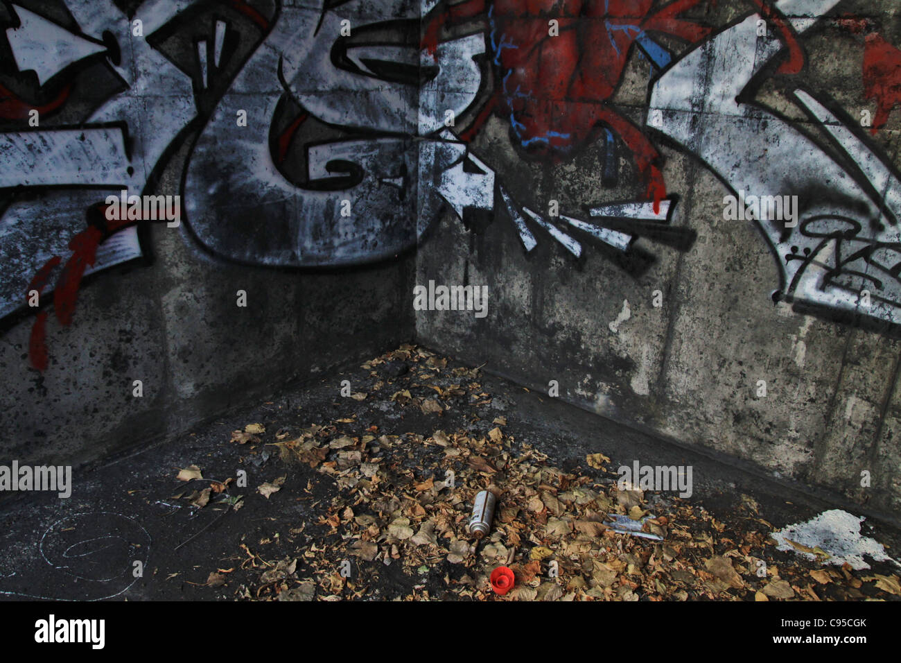 A discarded can of spray paint next to a graffiti covered wall. Stock Photo