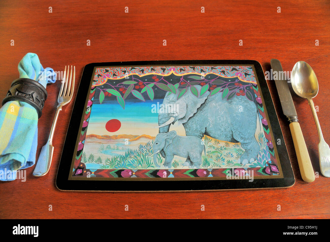 Asian elephant design place mat with with knife and fork and napkin set out on a wooden dining table. Stock Photo