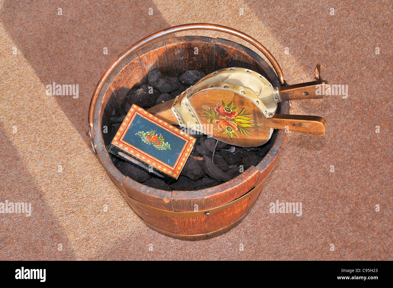An antique wooden coal bucket with coal, a box of matches and fire bellows. Stock Photo