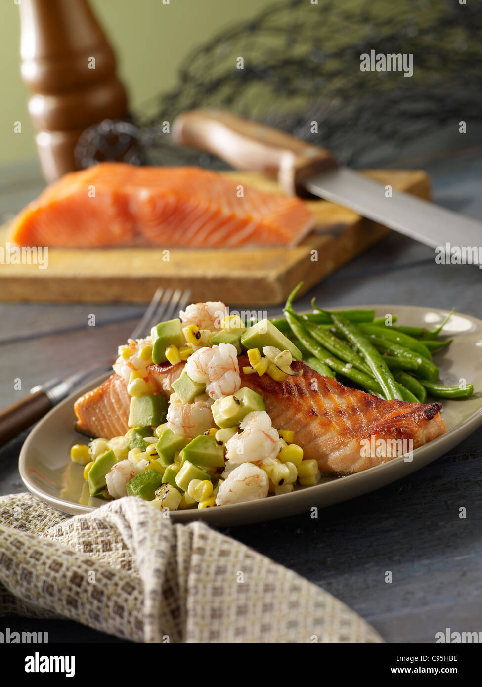 Grilled salmon topped with shrimp and avocado and served with green beans Stock Photo