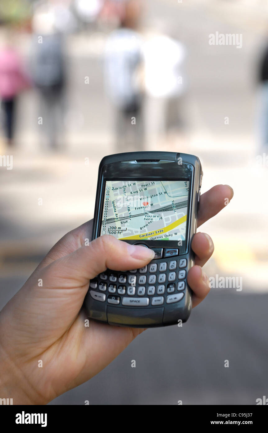 Person using BlackBerry 8310 Curve Smartphone on the street displaying GPS city map showing current location Stock Photo
