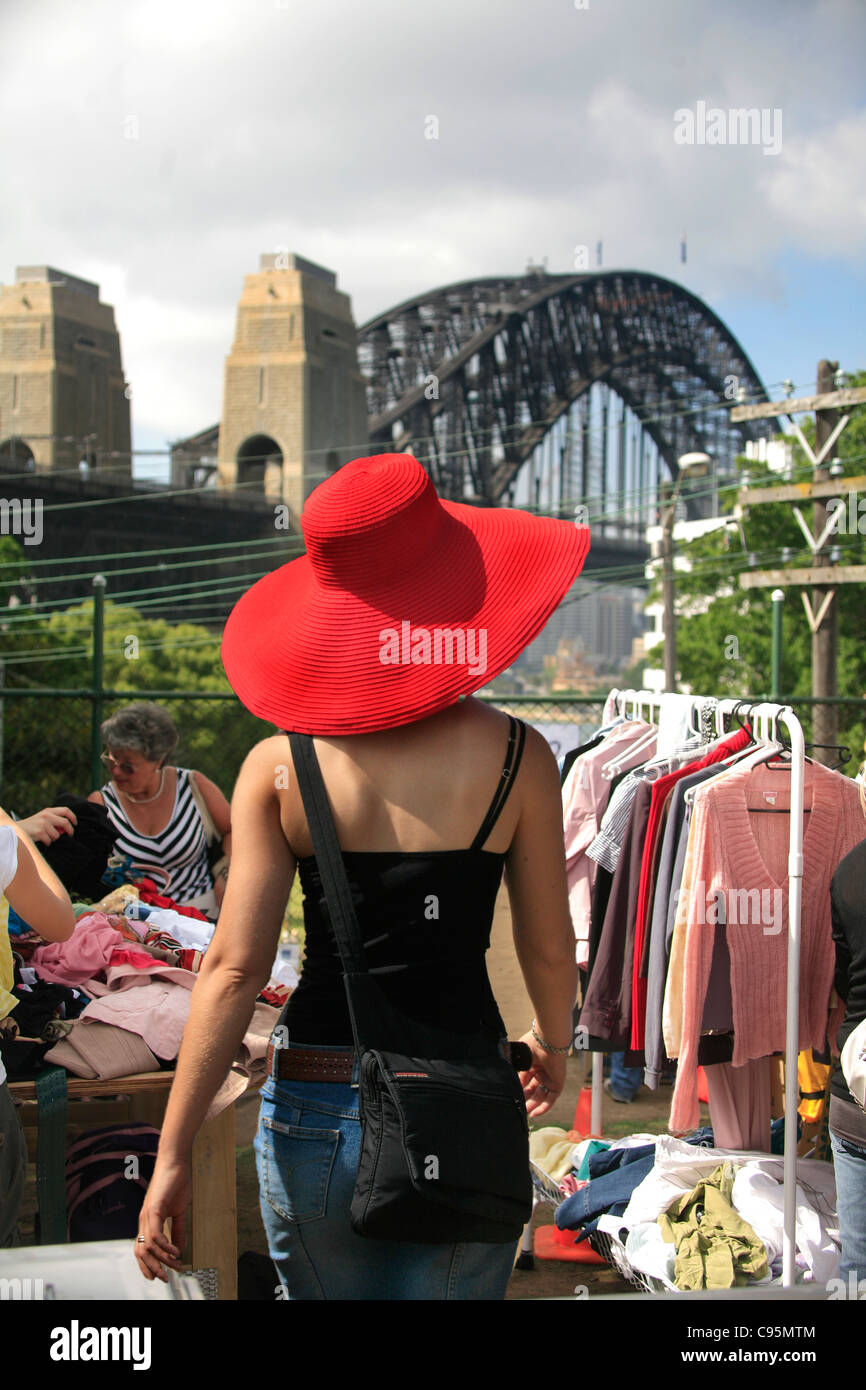 A stylish young woman in a red hat shops for clothing and fashion items at an outdoor market at Kirribilli in Sydney Australia Stock Photo