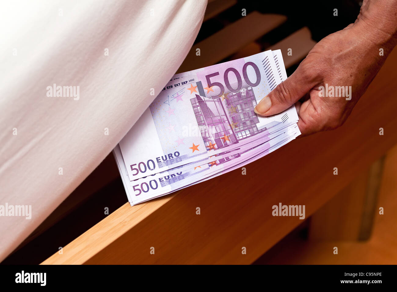 Many Euro notes are hidden under the bed. Stock Photo
