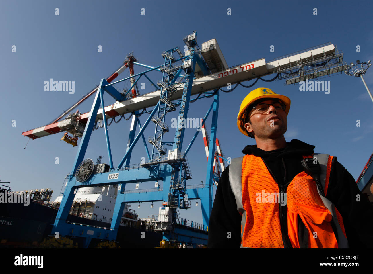 A worker stand amid industrial cranes lifting cargo containers onto