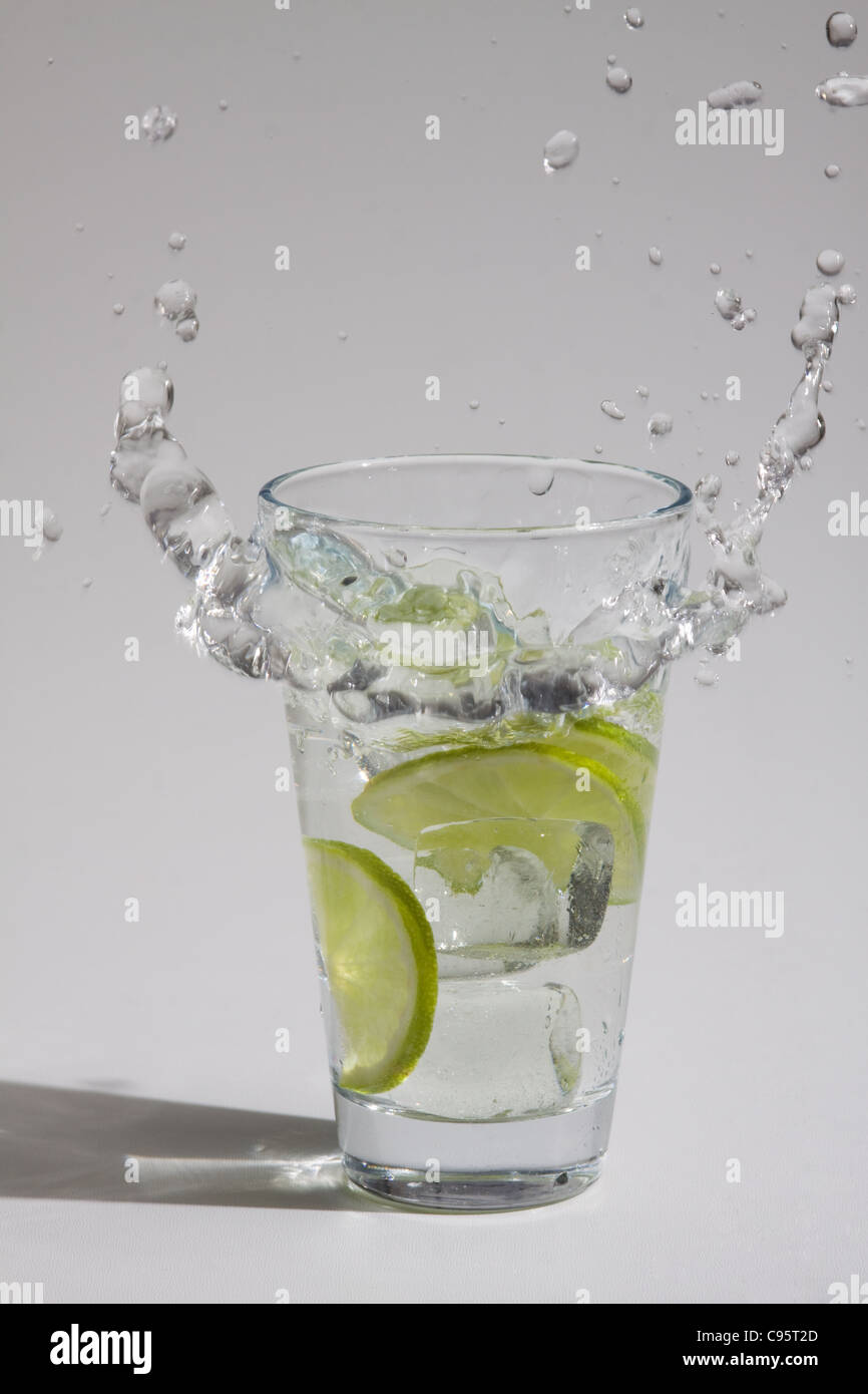 Ice cubes falling into a glass with water and lime Stock Photo - Alamy