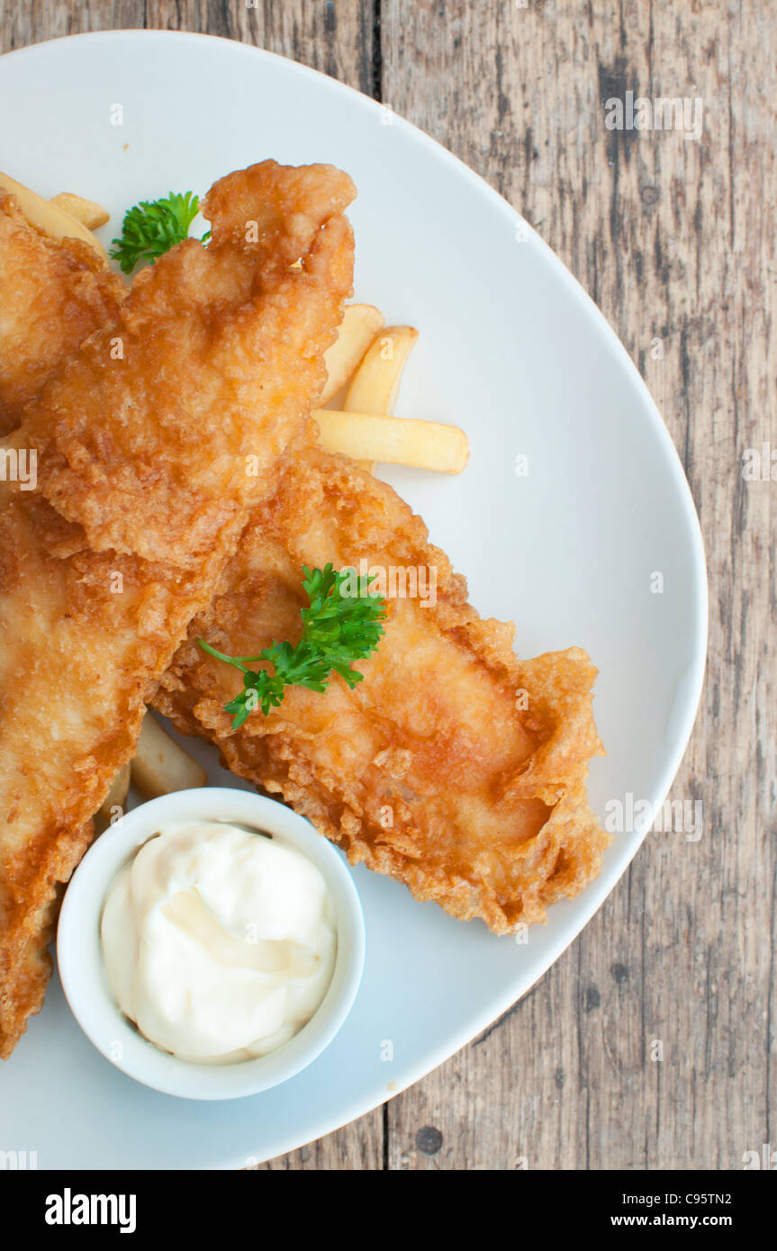 Two battered fish fillets on a plate with chips and mayonnaise Stock Photo