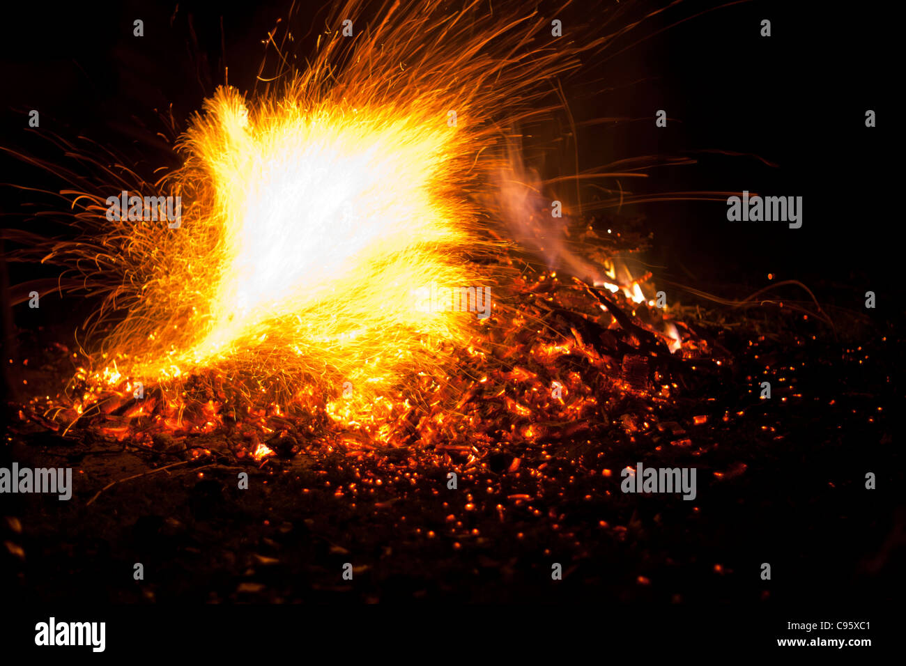 Fire with flames and sparks. Intense orange, yellow glow of bonfire against a black night background. Stock Photo