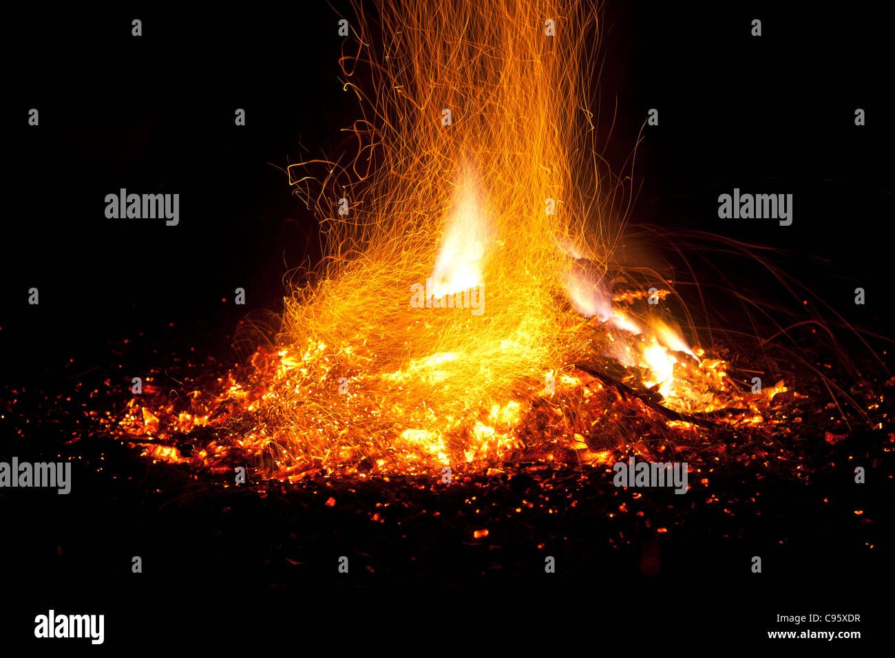 Fire with flames and sparks. Intense orange, yellow glow of bonfire against a black night background. Stock Photo