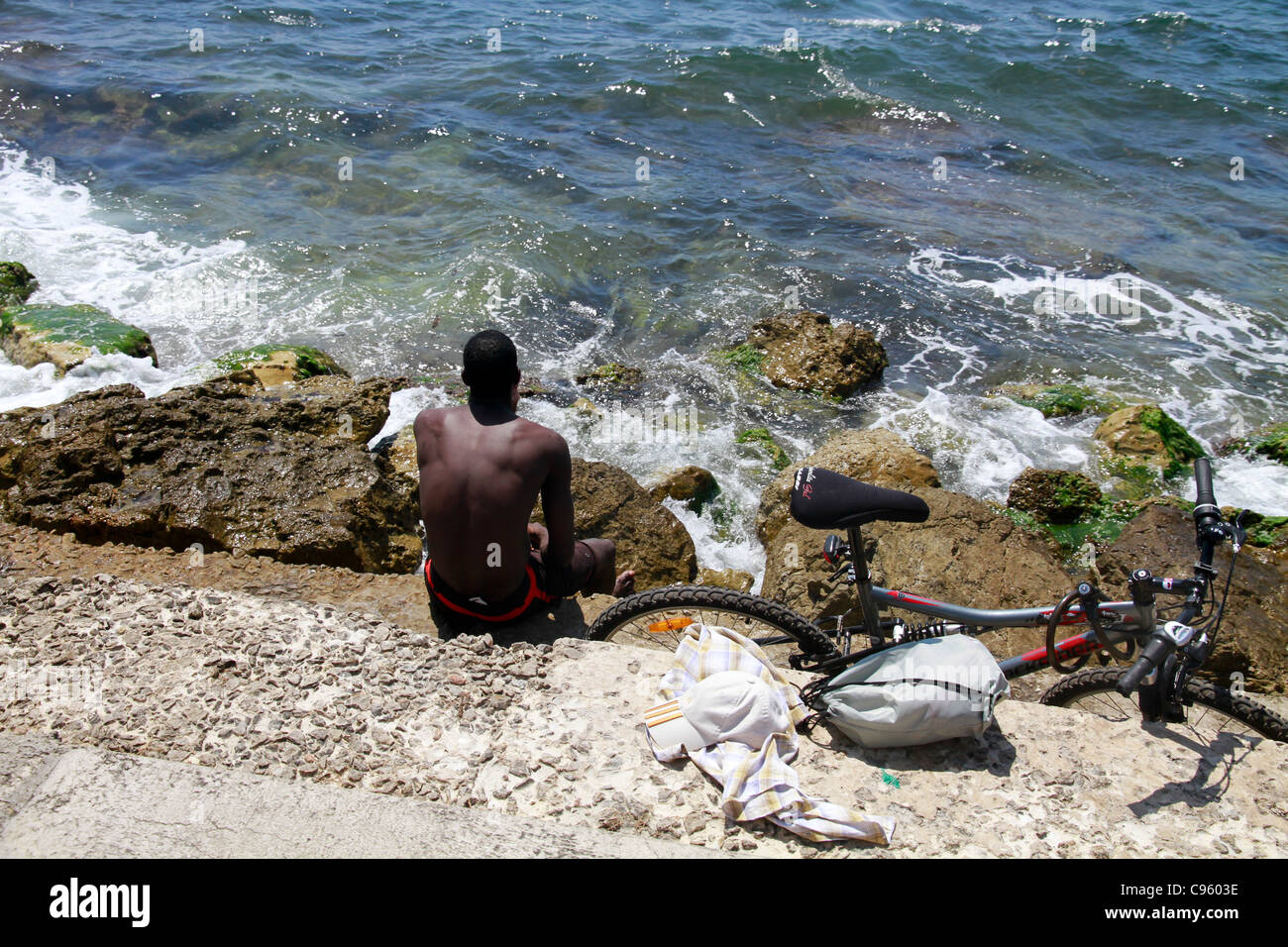 Black man cyclist relaxing and looking away to sea in Palma de Mallorca Majorca Spain Stock Photo