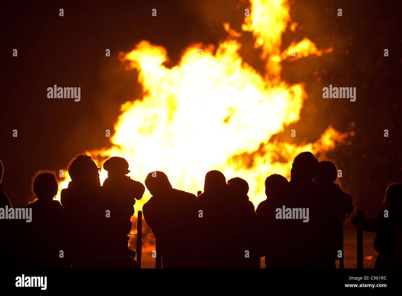 Families silhouetted by flames watching a bonfire on Guy Fawkes night, Wimbledon Park, London, UK. Photo:Jeff Gilbert Stock Photo