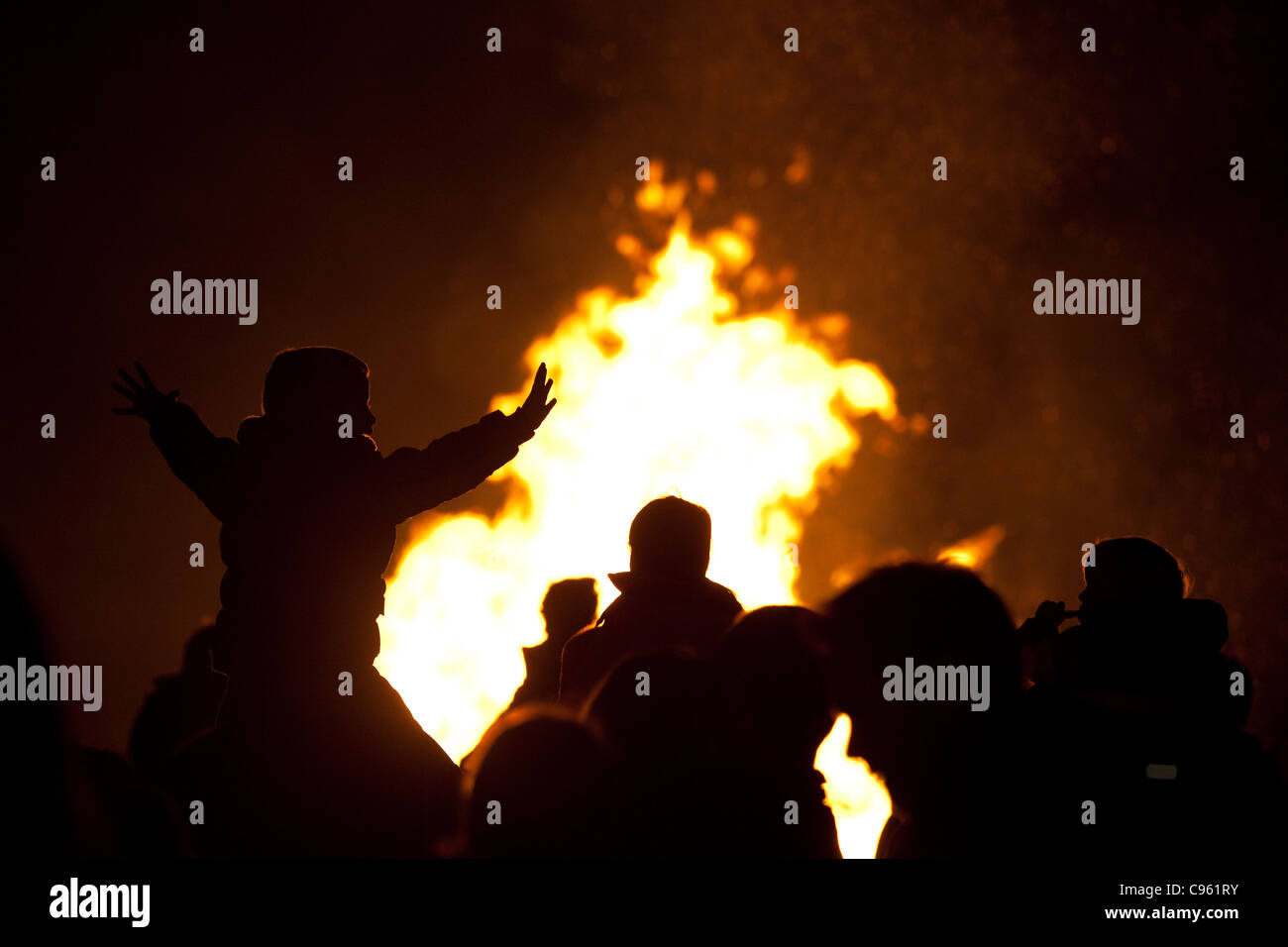 Families silhouetted by flames watching a bonfire on Guy Fawkes night, Wimbledon Park, London, UK. Photo:Jeff Gilbert Stock Photo