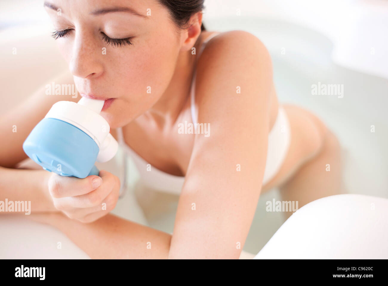 Water birth. Pregnant woman taking gas and air in a birthing pool. Stock Photo